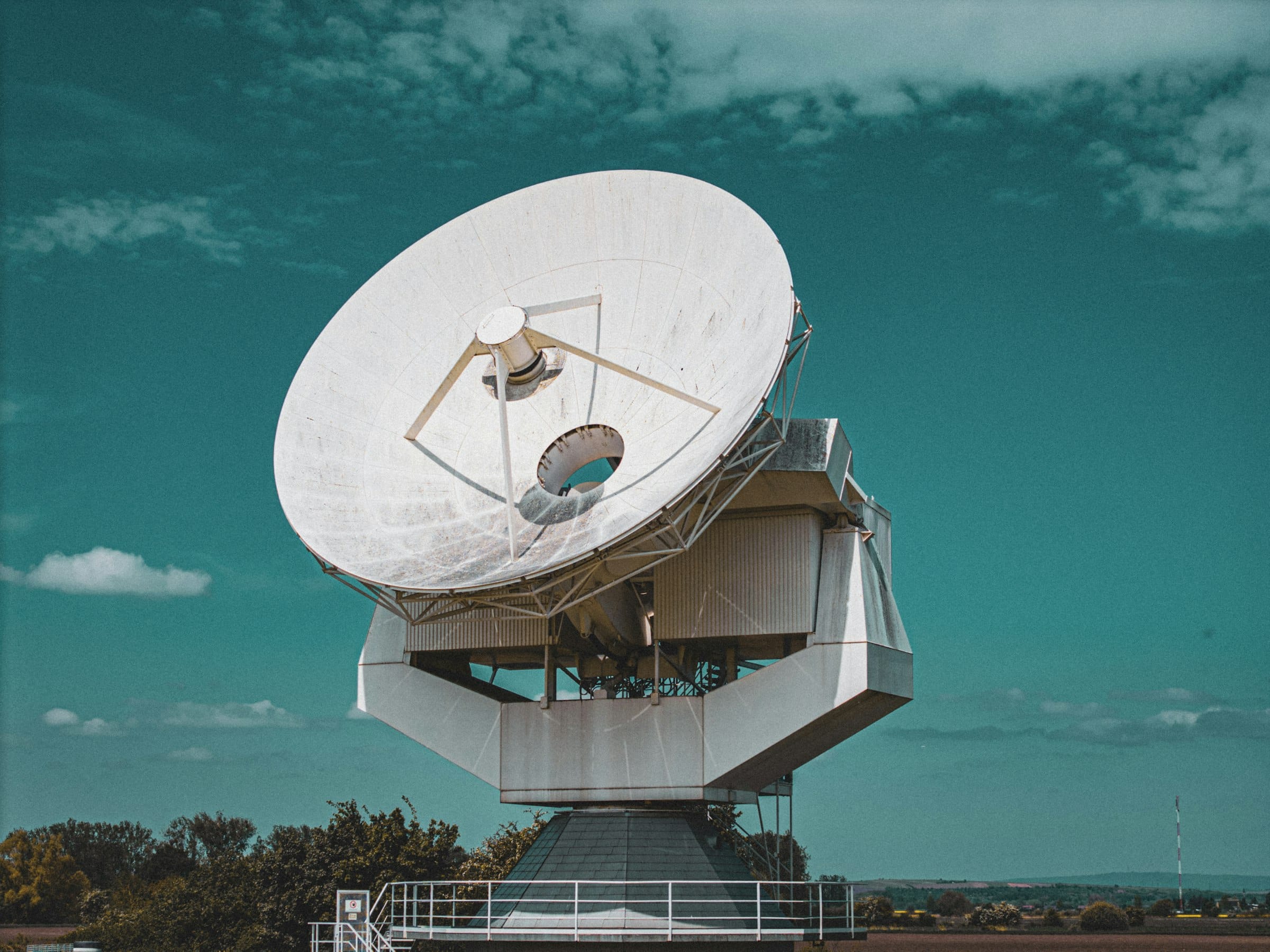 Large satellite ground station antenna under a blue sky